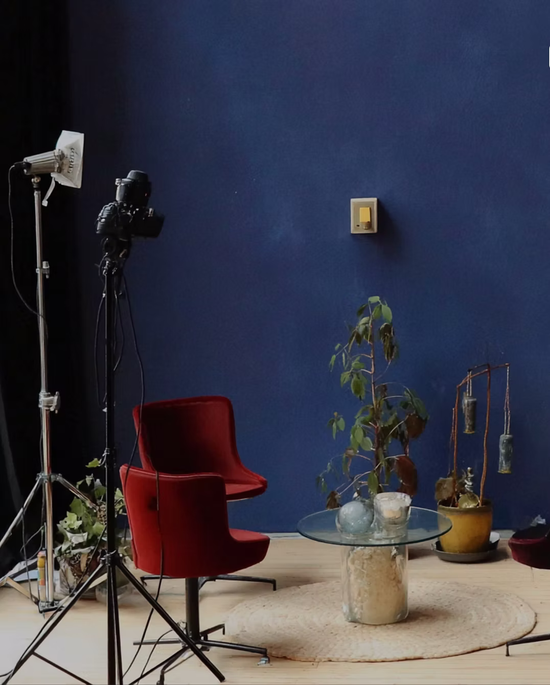 A blue-walled photography studio with a red chair, cameras and lighting equipment