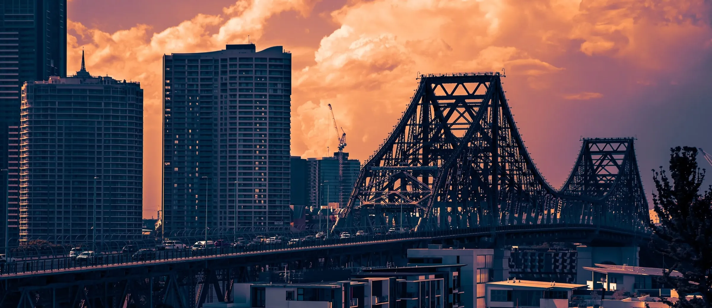 Brisbane's Story Bridge and city towers at sunset.