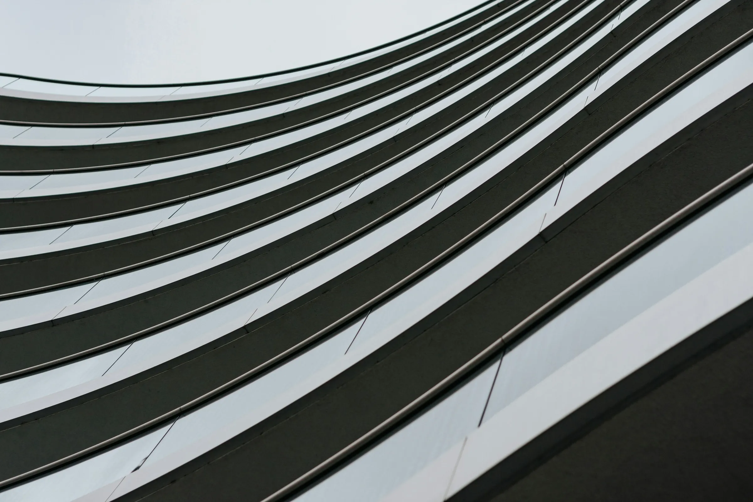 Looking up the sweeping curved balconies of a modern building against the sky.